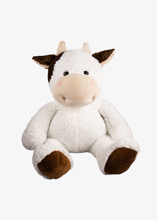 Peluche de vaca blanca con manchas negras de pie sobre fondo claro