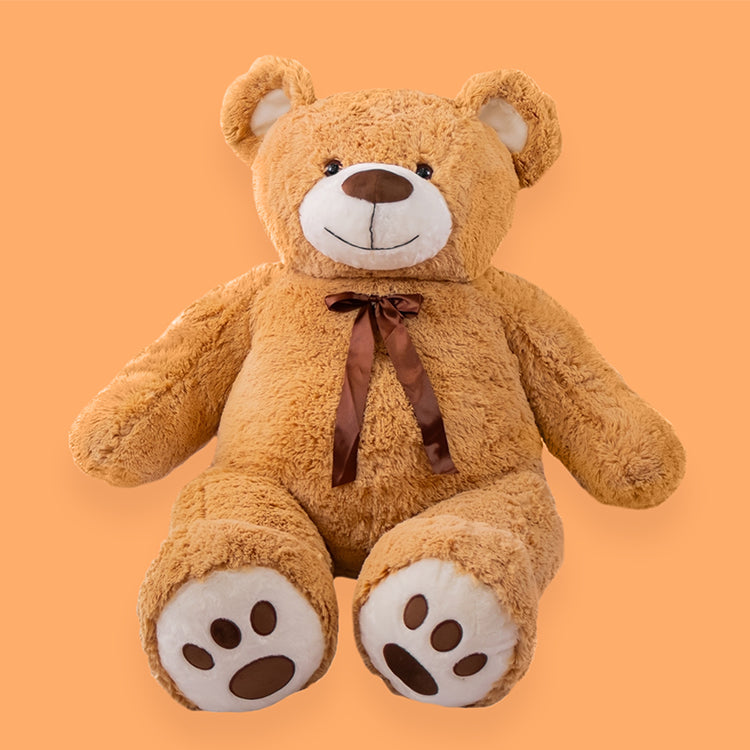 Oso de peluche clásico color café claro sentado sobre fondo naranja