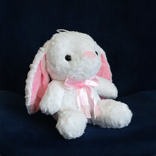 Conejo de peluche blanco con orejas largas, felpa suave y moño decorativo.