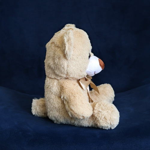 Oso de peluche color café, de felpa suave, sentado y con moño, ideal para regalo.