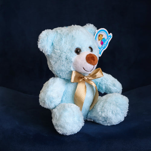 Oso de peluche color azul claro, de felpa suave, sentado y con moño decorativo.