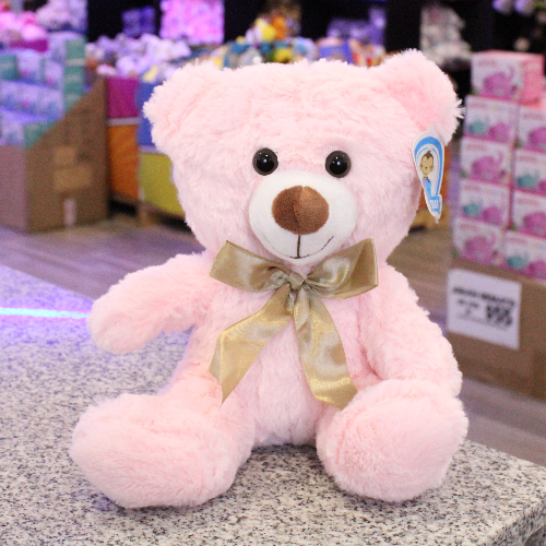 Oso de peluche color rosa con moño decorativo, ideal para regalo romántico o infantil.