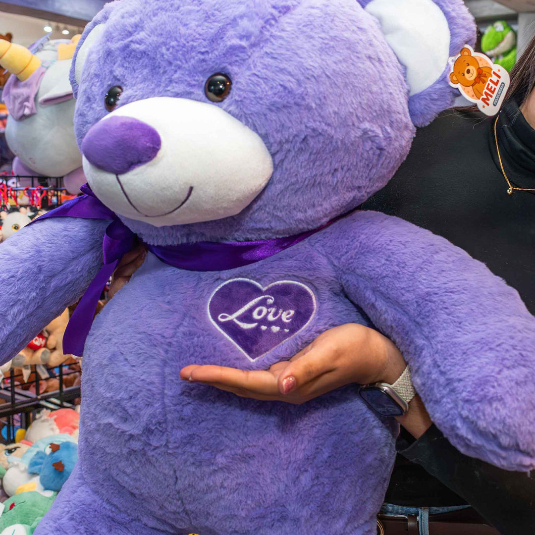 Oso de peluche meli super suave de color morado, ideal para regalos en cualrquier ocasión, en san valentin, regalar amor o decorar un espacio con un osito adorable.