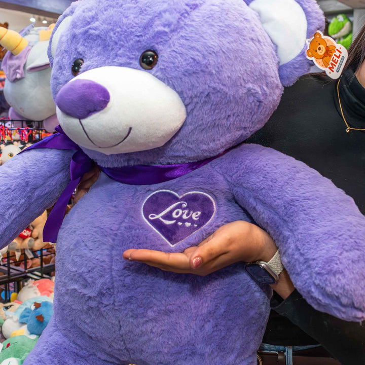 Oso de peluche meli super suave de color morado, ideal para regalos en cualrquier ocasión, en san valentin, regalar amor o decorar un espacio con un osito adorable.
